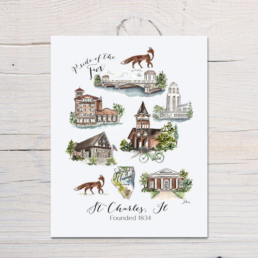 A vertical white art print featuring a watercolor collage of St. Charles, Illinois landmarks, foxes, and script text reading 'Pride of the Fox' and 'St Charles, Ill Founded 1834,' shown hanging against a light wood plank background.